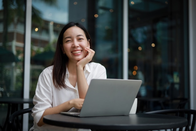 Foto mulher asiática em um café trabalhando em um laptop