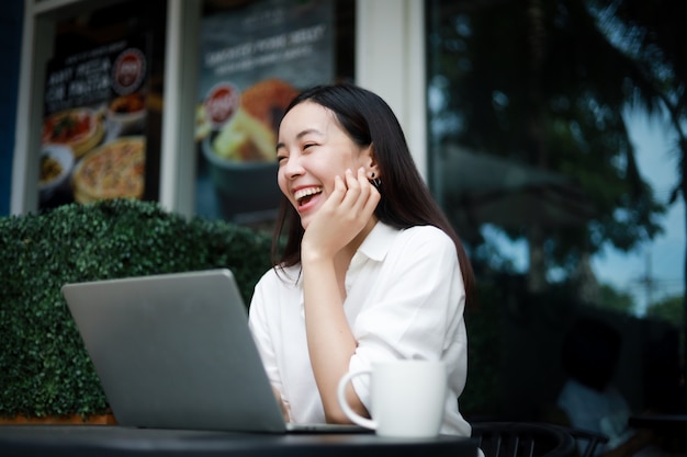 Foto mulher asiática em um café trabalhando em um laptop