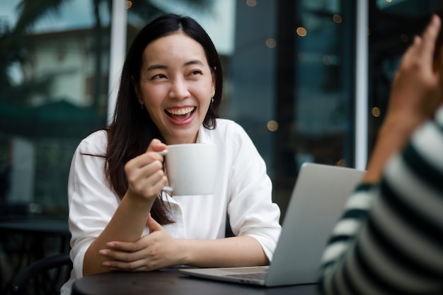 Foto mulher asiática em um café trabalhando em um laptop