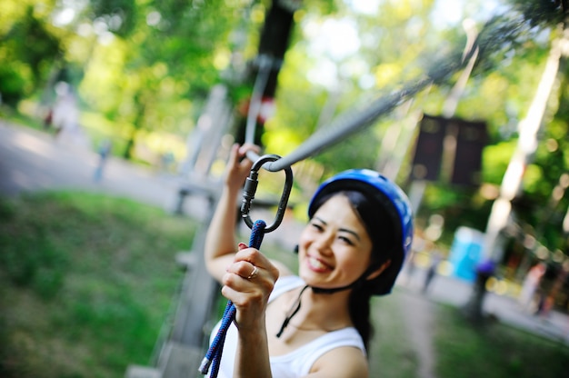 Mulher asiática em um capacete azul, corda de escalada