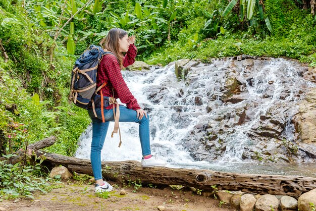 Mulher asiática em um chapéu e mochila olhando ao redor