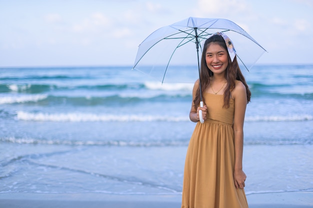 Mulher asiática em um vestido marrom Relaxe se sentir feliz. Com uma viagem à praia