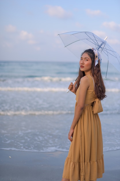 Mulher asiática em um vestido marrom Relaxe se sentir feliz. Com uma viagem à praia