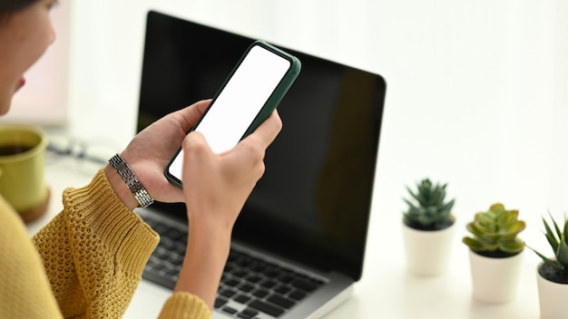 Mulher asiática encantadora usando um telefone celular enquanto relaxa no escritório