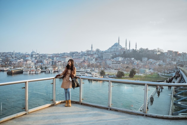 Foto mulher asiática encostada em uma ponte olhando a vista panorâmica da bela cidade de istambul e bósforo