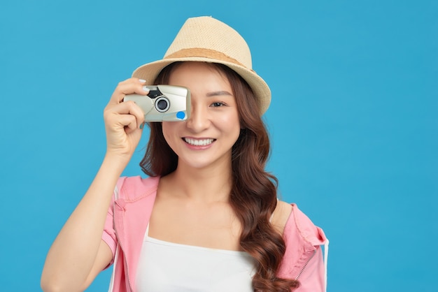 Mulher asiática energética atraente e feliz segurando Cemara isolada no fundo azul do estúdio