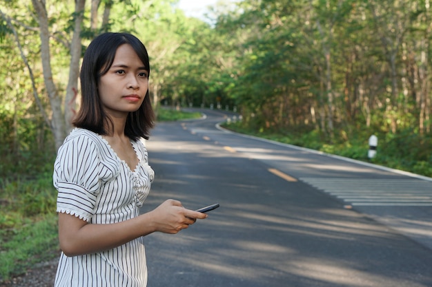 Mulher asiática, esperando um ônibus na berma da estrada