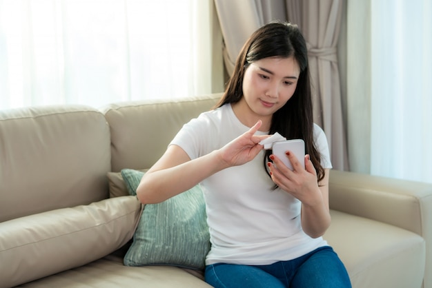 Mulher asiática está pulverizando álcool no celular