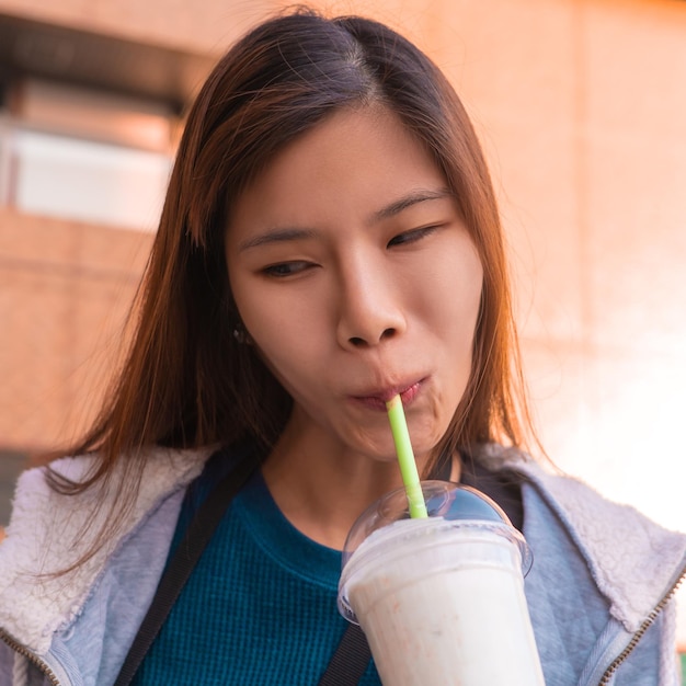 Foto mulher asiática está se divertindo bebendo milk-shake