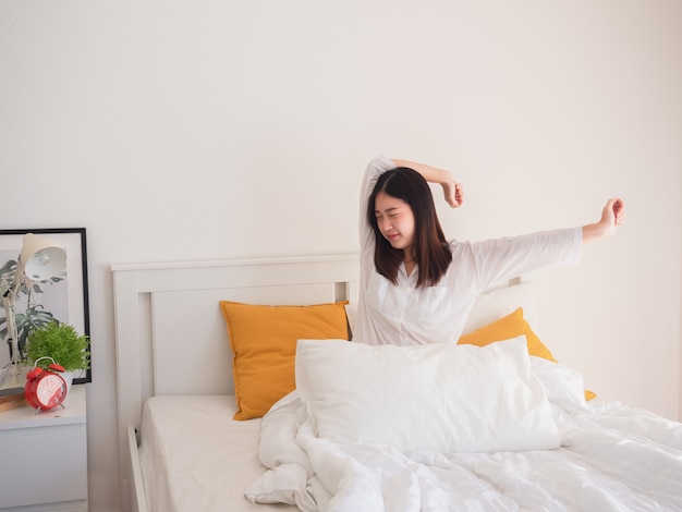 Mulher asiática, estendendo-se na cama depois de acordar