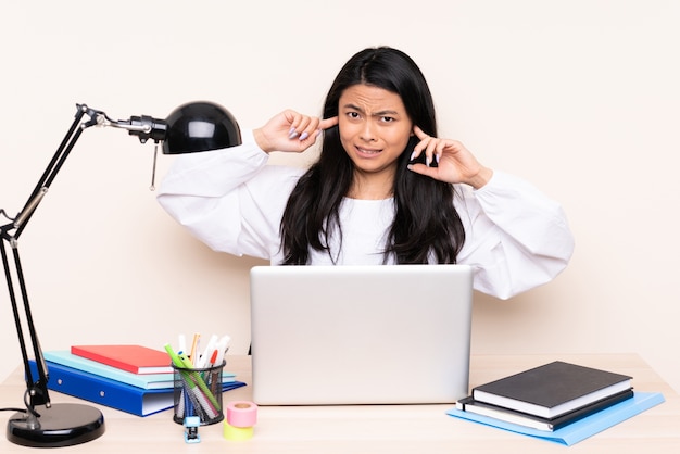 Mulher asiática estudante em um local de trabalho com um laptop isolado