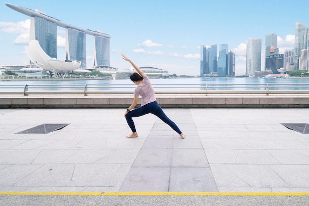 Mulher asiática fazendo alongamento na ponte da esplanada
