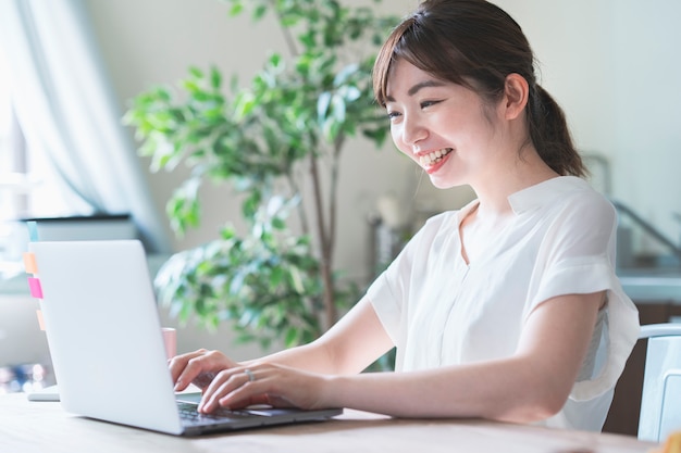 Mulher asiática fazendo trabalho remoto com laptop