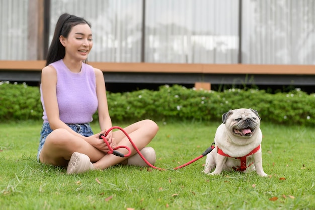 Foto mulher asiática feliz a brincar com um cãozinho no quintal.