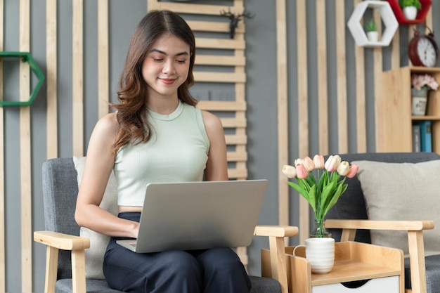 Foto mulher asiática feliz acordando com notebook na sala de estar em casa