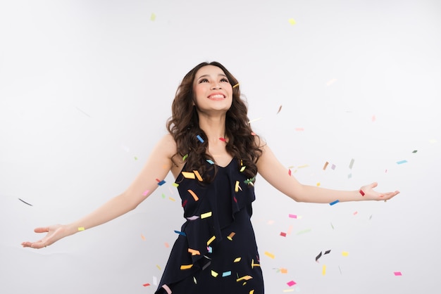 Mulher asiática feliz comemorando com confete no fundo branco
