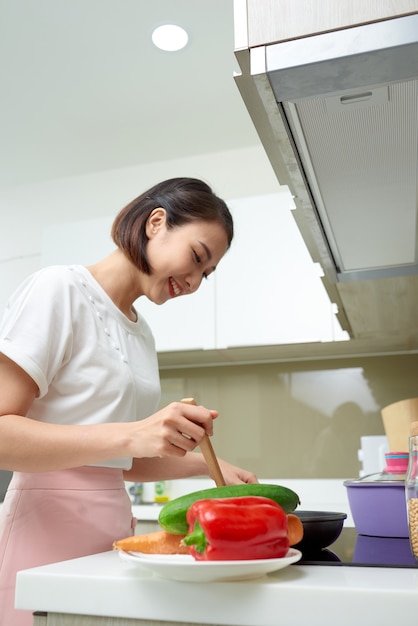 Mulher asiática feliz cozinhando na cozinha.