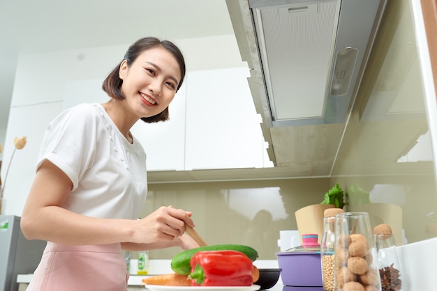 Mulher asiática feliz cozinhando na cozinha.