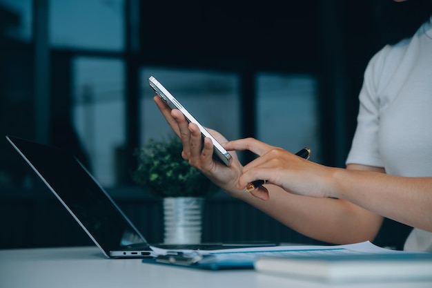 Mulher asiática feliz e excitada olhando para a tela do telefone celebrando uma vitória on-line, jovem asiática gritando de alegria, isolada sobre um fundo branco desfocado.