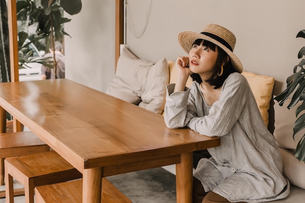 Foto mulher asiática feliz olhando para a frente e sentado no sofá no café