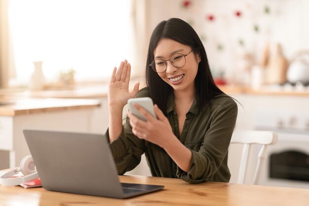 Mulher asiática feliz olhando para a tela do smartphone e gesticulando