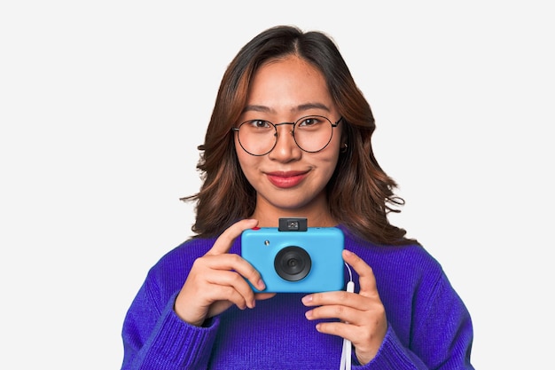 Mulher asiática feliz segurando uma câmera retrô