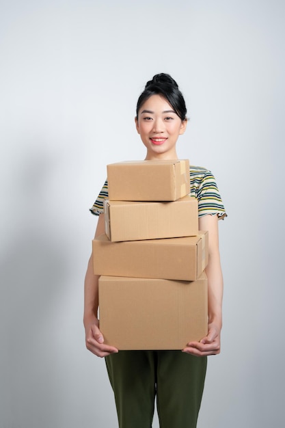 Mulher asiática feliz segurando uma pilha de caixas conceito de entrega compras ou negócios fundo branco