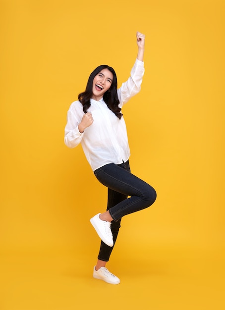 Mulher asiática feliz sorrindo e em pé com a mão celebrando o gesto em amarelo.