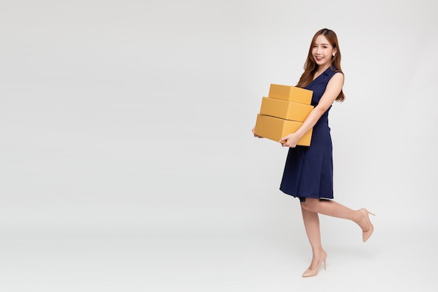 Mulher asiática feliz sorrindo e segurando a caixa de pacote isolada no fundo branco, conceito de serviço de entrega e correio de entrega, composição de corpo inteiro