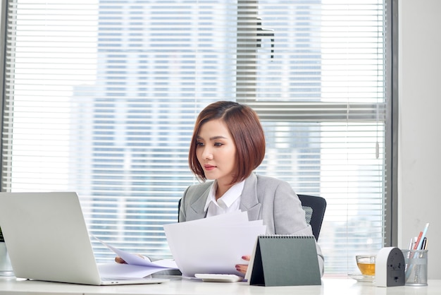Mulher asiática feliz trabalhando no escritório. Mulher passando por uma papelada no local de trabalho.
