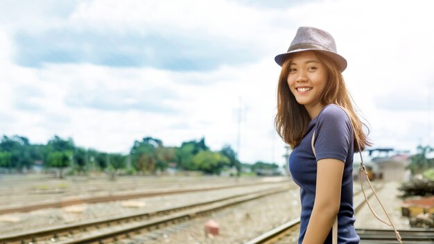 Mulher asiática feliz vai viajar em um dia ensolarado na ferrovia