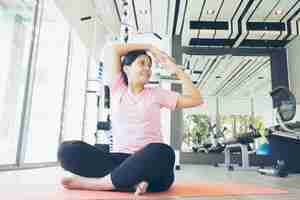 Foto mulher asiática fitness warm up antes de fazer exercício no ginásio, idade média feminino malhando yoga
