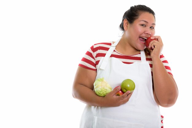 Mulher asiática gorda e feliz sorrindo enquanto segura vegetais