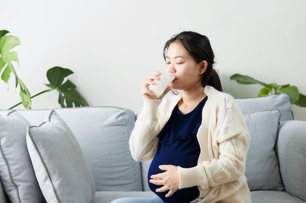 Mulher asiática grávida bebendo leite