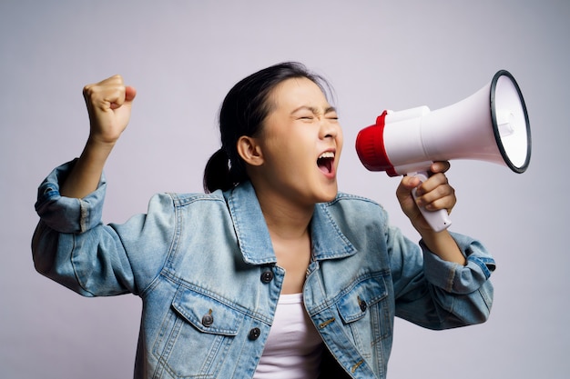 Mulher asiática gritando com megafone isolado.