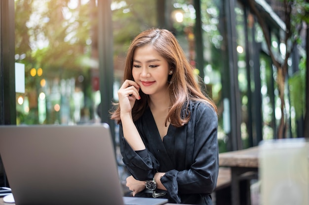 Mulher asiática inteligente está trabalhando com o computador portátil