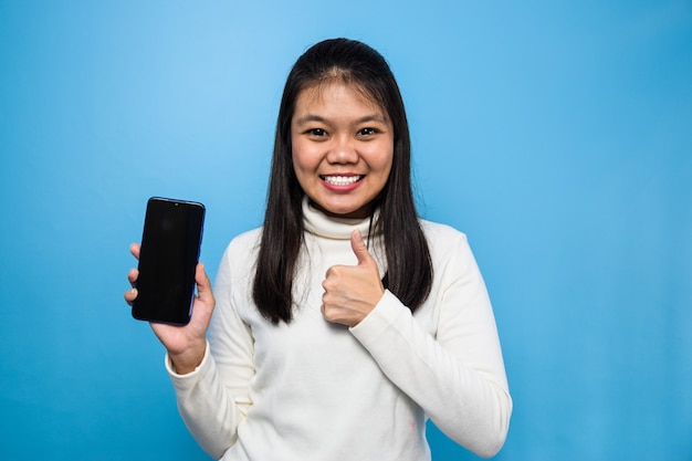 Mulher asiática isolada em azul mostrando tela em branco para celular bons aplicativos aplicativos recomendados