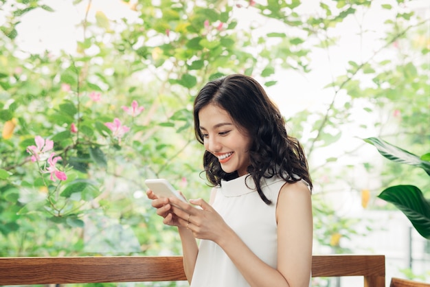 Mulher asiática jovem confiante em desgaste casual inteligente, digitando no telefone.