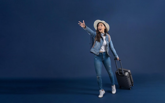 Mulher asiática jovem feliz segurando a bagagem e corra para o aeroporto na cor azul