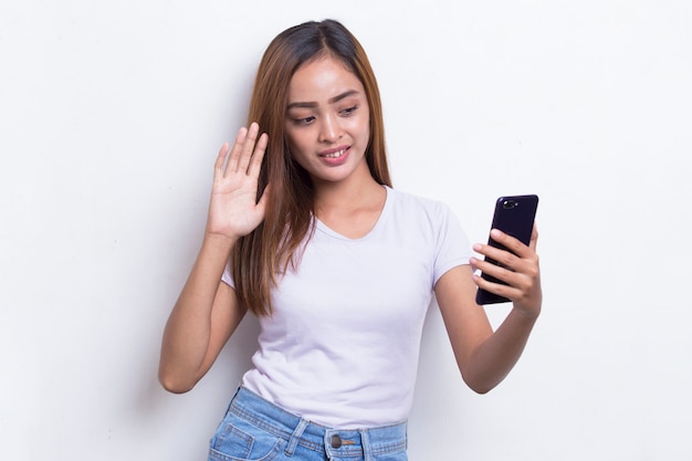 Mulher asiática jovem feliz usando telefone celular isolado no fundo branco