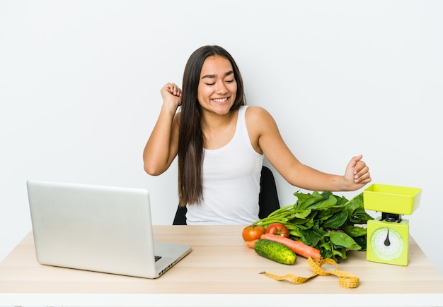 Mulher asiática jovem nutricionista isolada na parede branca, dançando e se divertindo.