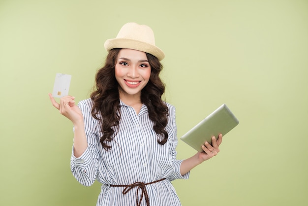 Mulher asiática jovem sorridente segurando um cartão de crédito e um tablet