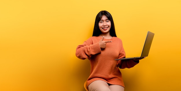 Mulher asiática, laptop e feliz em trabalhar Foto de uma linda mulher asiática que está feliz em trabalhar em casa. usando um estúdio de computador laptop amarelo trabalhar em casa conceito