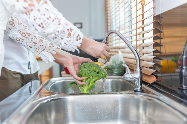 Mulher asiática lava legumes para cozinhar comida com conceito de namorado