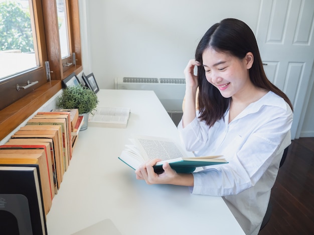 Mulher asiática lendo livro na sala de trabalho