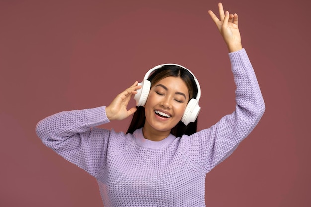 Mulher asiática louca em fones de ouvido cantando regozijando-se e mostrando gesto de paz