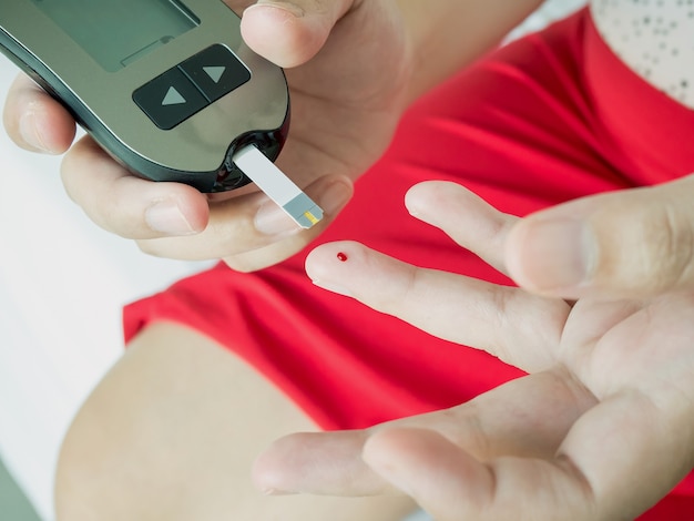 Foto mulher asiática medindo o nível de glicose com medidor digital de glicose, teste de diabetes