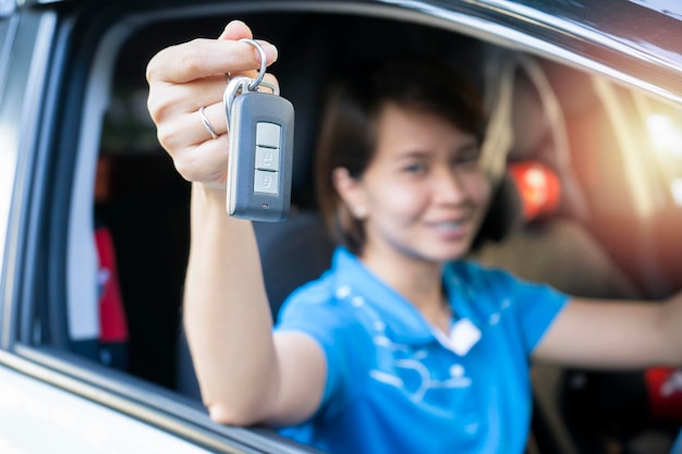 Mulher asiática mostrando a chave do carro novo retrato de um jovem motorista entusiasmado segurando uma chave depois de comprar um carro novo