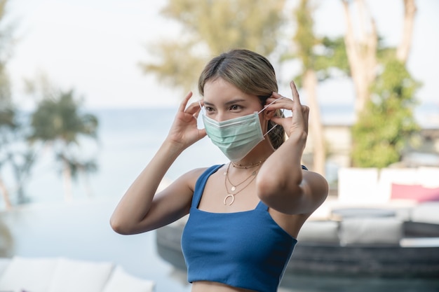 Mulher asiática mostrando passo para usar uma máscara médica.