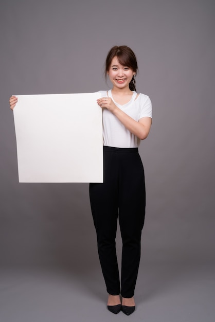 Mulher asiática mostrando um quadro branco vazio com copyspace